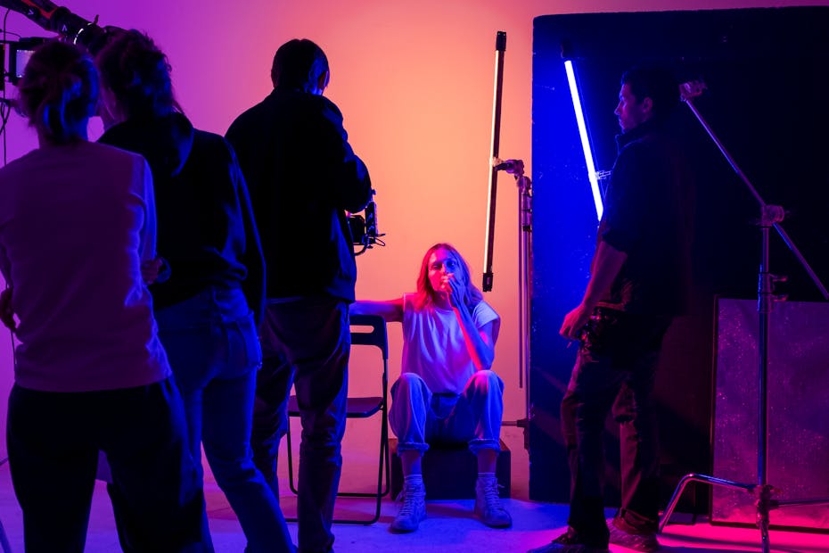 Artistic photoshoot session with neon lighting, capturing a model in a creative studio environment.