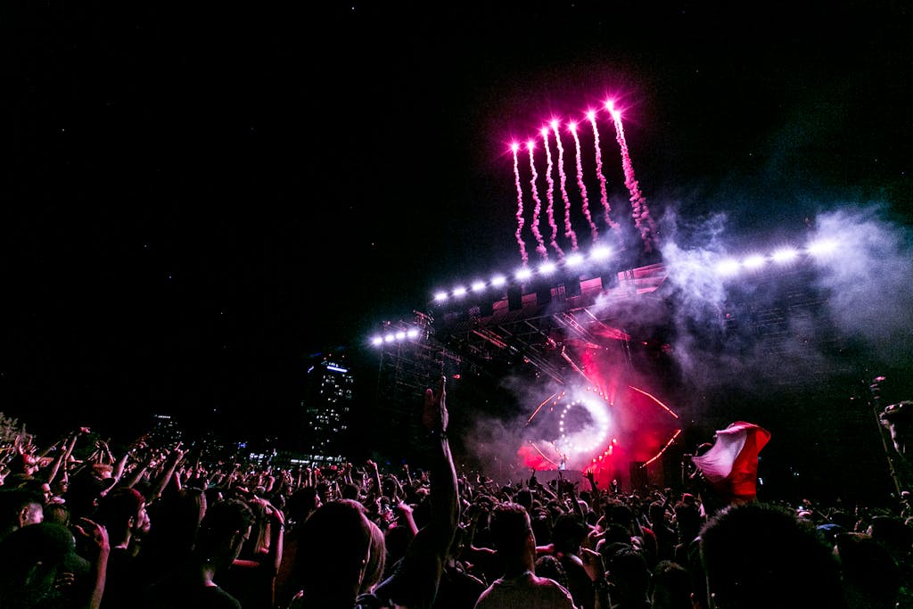 A vibrant nighttime festival with fireworks, showcasing a lively crowd and performance stage.
