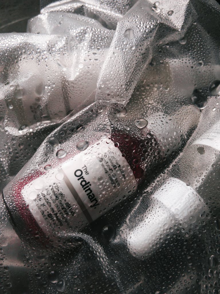 Detail shot of skincare serum bottles with water droplets, emphasizing freshness and hydration.